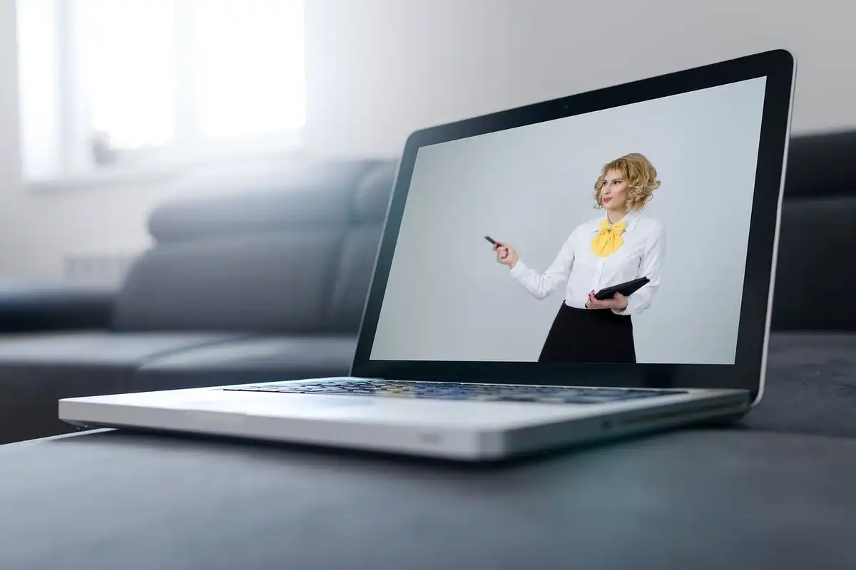 O mentoră prezintă la distanță un program de accelerare, pe ecranul unui laptop așezat pe canapea
