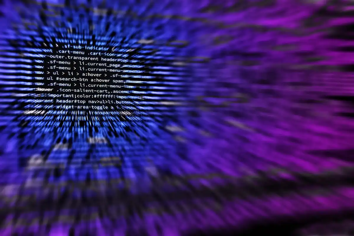 Linii de cod estompate, în nuanțe violet, pe un ecran de programator