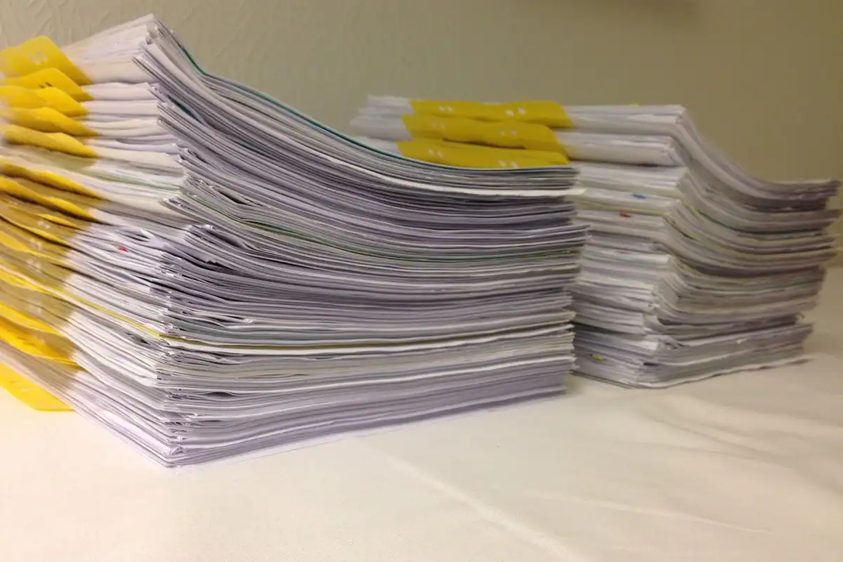 Un teanc înalt de dosare cu documente, pregătite pentru depunerea cererii de finanțare