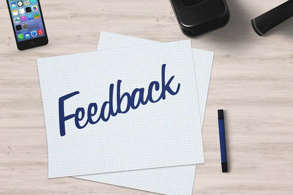 O foaie cu cuvântul feedback, un pix și un telefon pe un birou de lemn