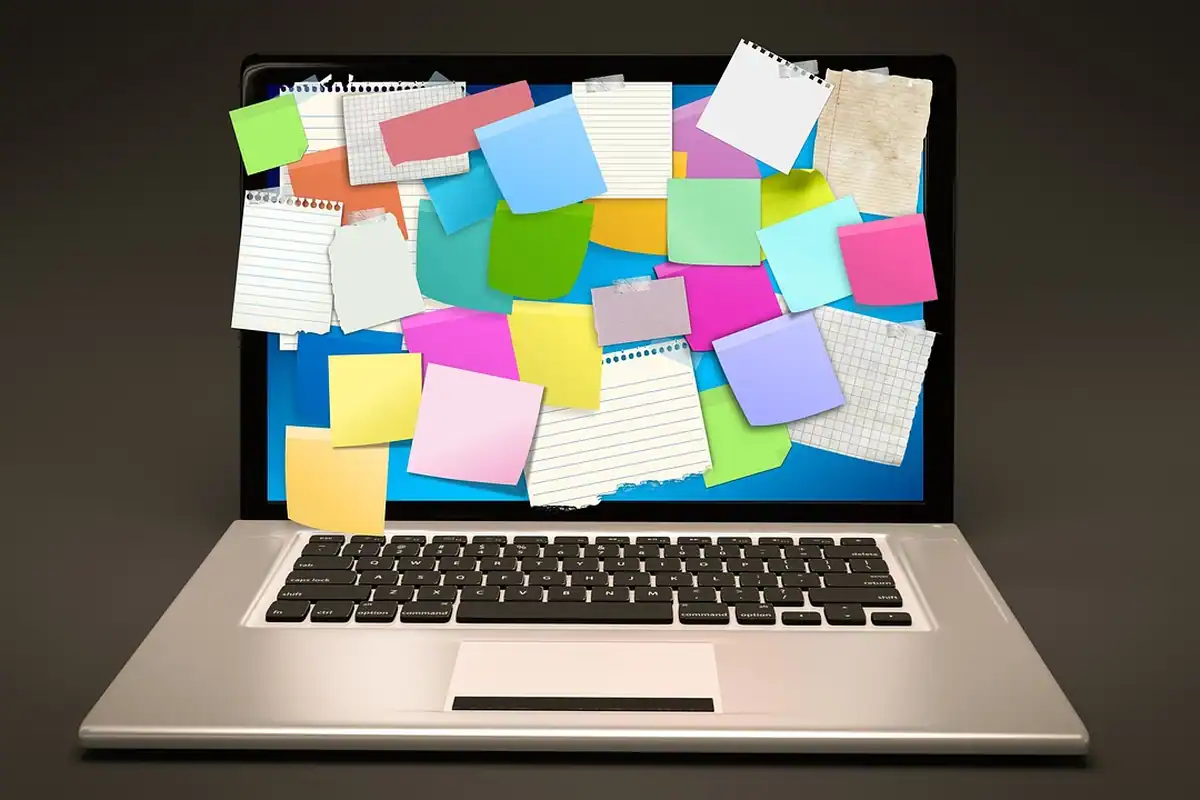 Un laptop cu ecranul acoperit de notițe adezive colorate, ca la completarea unui canvas